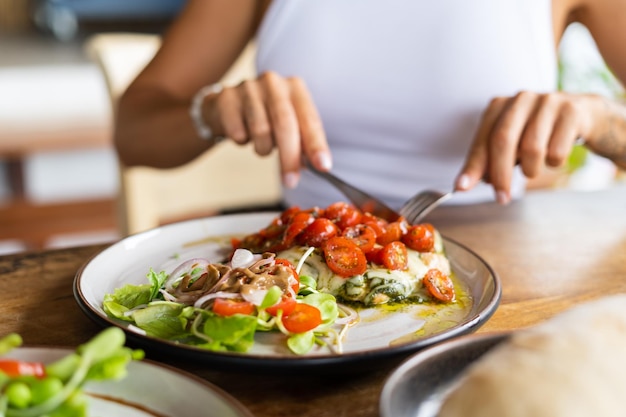 Foto donna che mangia il pesto di pollo con formaggio e pomodori nel caffè estivo