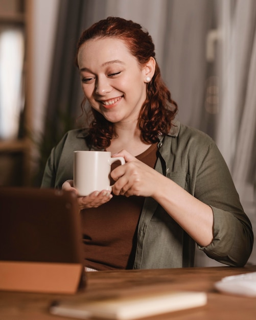 写真 家でコーヒーを飲み、タブレットを使用している女性