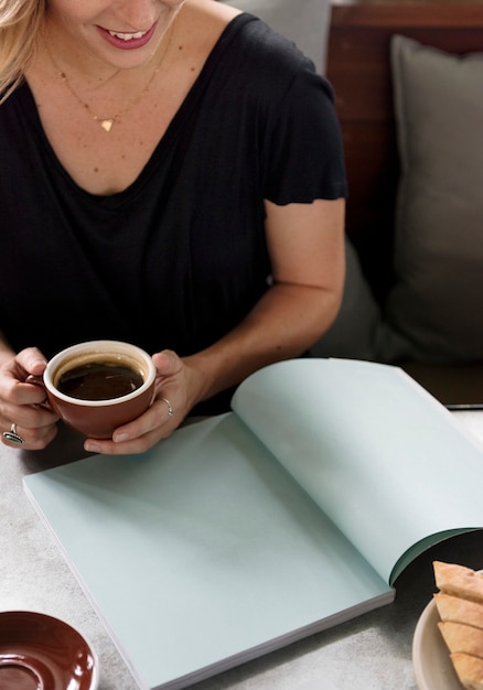 Foto donna che mangia un caffè mentre leggendo una rivista