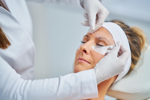 Woman having cosmetology eyebrows treatment in beauty salon