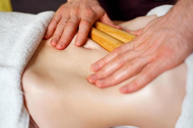 Woman having a creole massage of the abdominal area with bamboo sticks