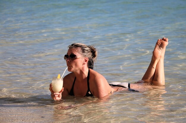 Photo woman having drink while relaxing at beach