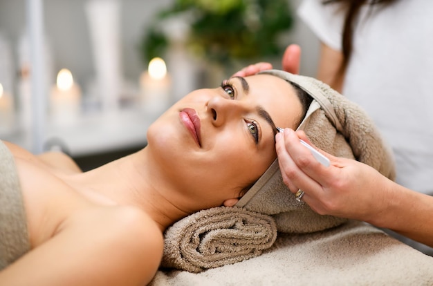 Photo woman having eyebrows treatment in spa salon