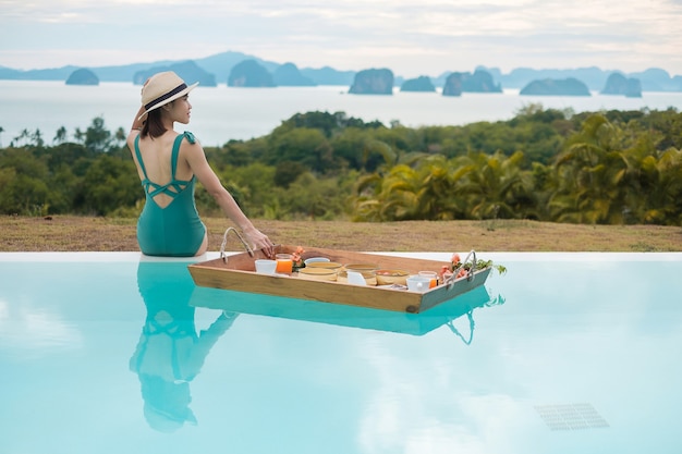 woman having floating breakfast tray in luxury pool hotel