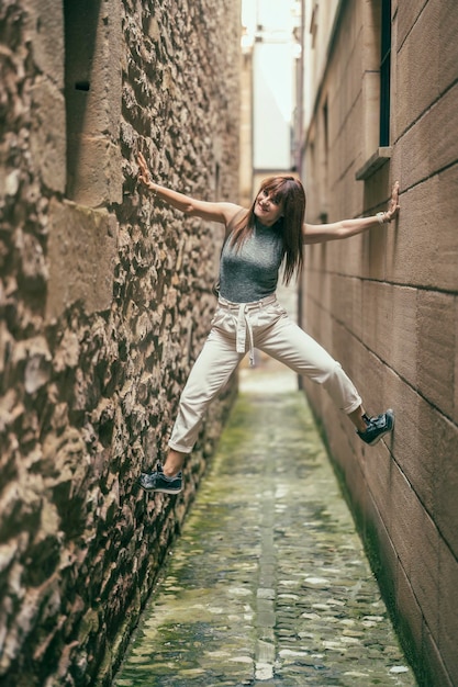 Woman having fun climbing up between the walls of two buildings