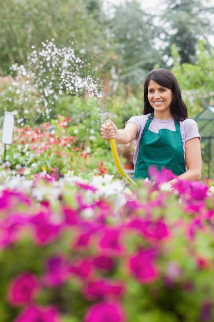 ホースで植物に水をあたっている間、楽しい女性