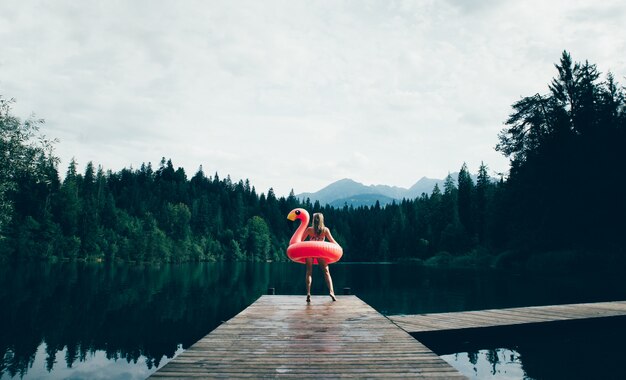 Woman having fun with flamingo at lakeside place