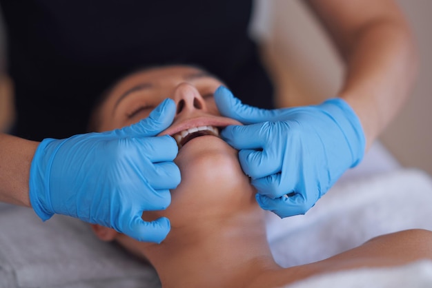 Woman having mouth massage in blue gloves