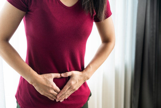 Donna che ha mal di stomaco doloroso a casa. gastrite cronica. concetto di gonfiore addominale