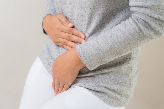 Foto donna che ha mal di stomaco doloroso con le mani che tengono premendo la sua parte inferiore della biforcazione dell'addome