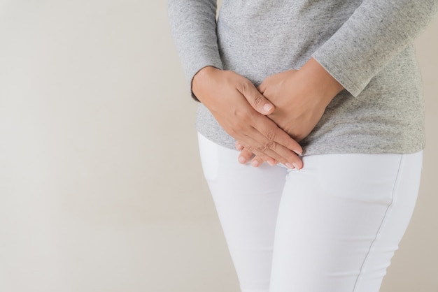 Woman having painful stomachache with hands holding pressing her crotch lower abdomen