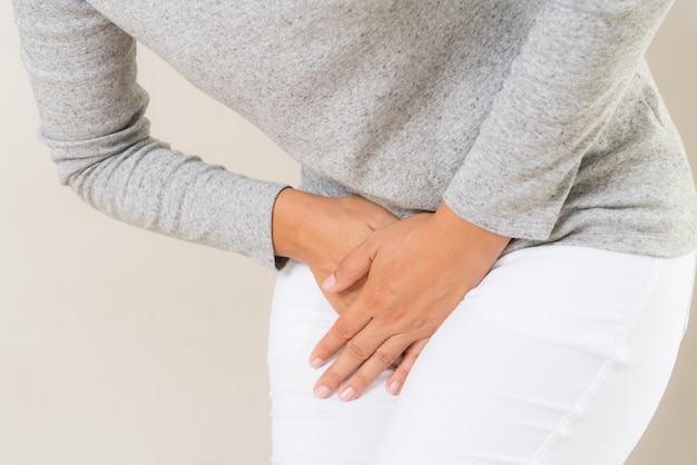 Woman having painful stomachache with hands holding pressing her crotch lower abdomen.