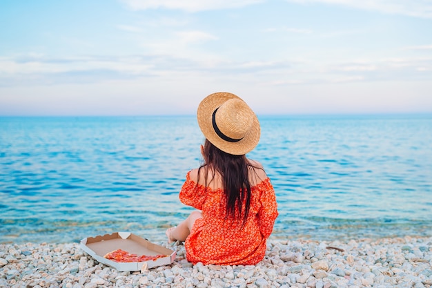 Donna che ha un picnic con pizza sulla spiaggia