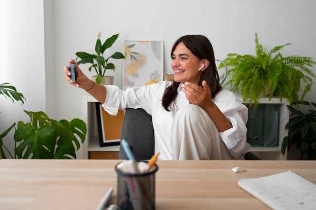 Foto donna che fa una videochiamata a casa con uno smartphone