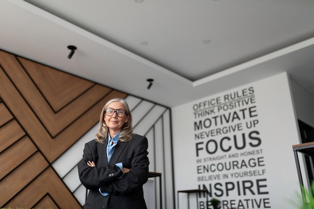 Женщина-глава компании в деловой одежде стоит посреди современного офиса