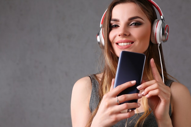 Woman in headphones holding smartphone