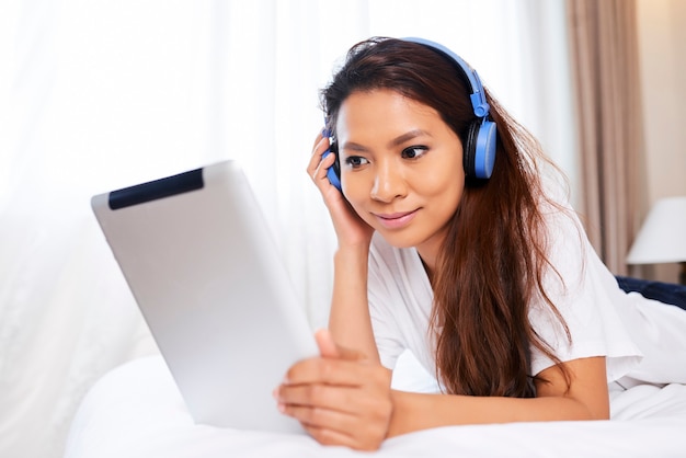 Woman in Headphones Relaxing on Bed