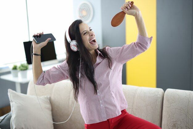 Photo woman in headphones singing to a brush