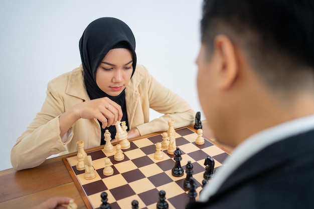 Woman in headscarf holding chess pieces while playing chess