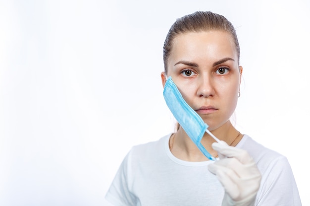 Woman health worker demonstrates how to wear a protective medical surgical mask against the virus. Isolated on white background