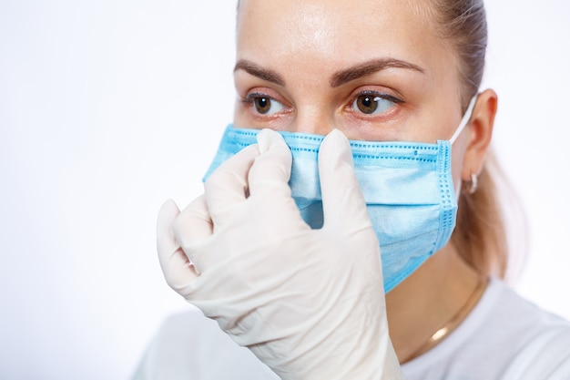 Woman health worker demonstrates how to wear a protective medical surgical mask against the virus. Isolated on white background