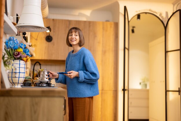 Woman heats a kettle at kitchen