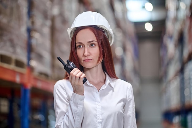 Woman in helmet holding walkie-talkie near face