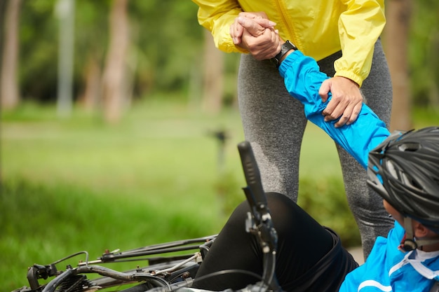 男が自転車から落ちたのを助ける女性