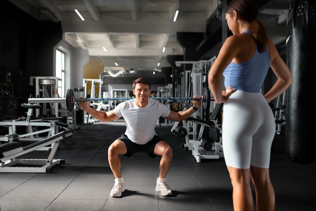 Foto donna che aiuta l'uomo in palestra