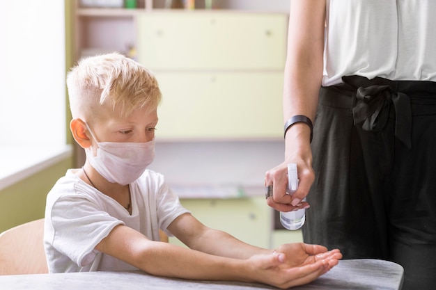 Foto donna che aiuta uno studente a disinfettare le sue mani