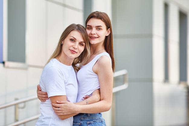 A woman and her adult daughter in bright clothes are standing and looking