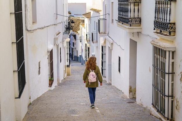 Woman on her back walking through a typical Andalusian village of white houses and metal bars on the windows Medina Sidonia Cadiz