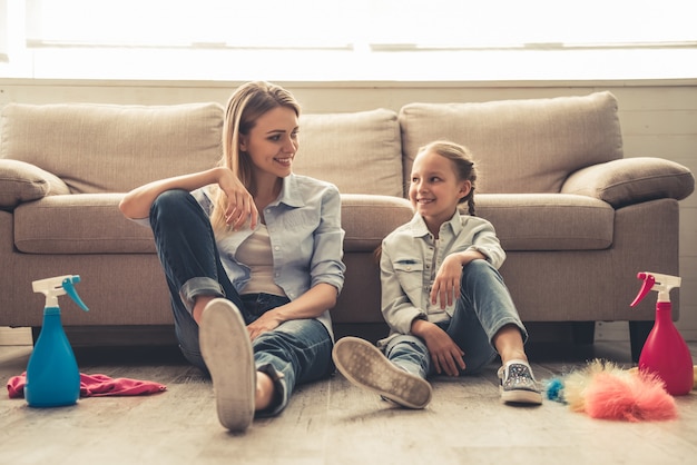 La donna e la sua piccola figlia sveglia sono sedute sul pavimento.