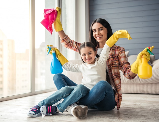 Woman and her daughter are sitting on the floor. Cleaning concept