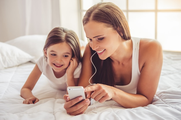 Woman and her daughter in earphones are listening to music