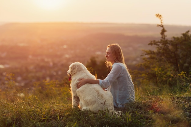 Donna e il suo cane seduti sulla collina in campagna