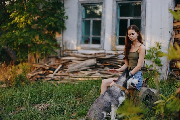 Woman and her husky dog happily playing outdoors in the park among the trees smile with teeth in the autumn walk with her pet