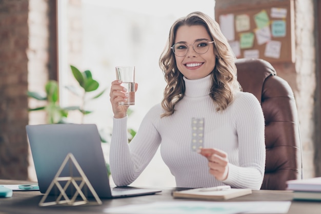 woman in her office taking pills