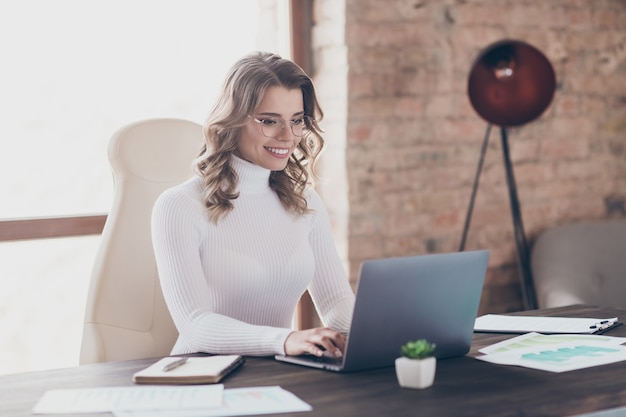 Donna nel suo ufficio che lavora al computer portatile