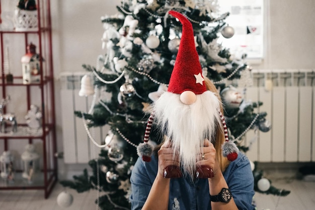 家でクリスマスのおもちゃの後ろに隠れている女性