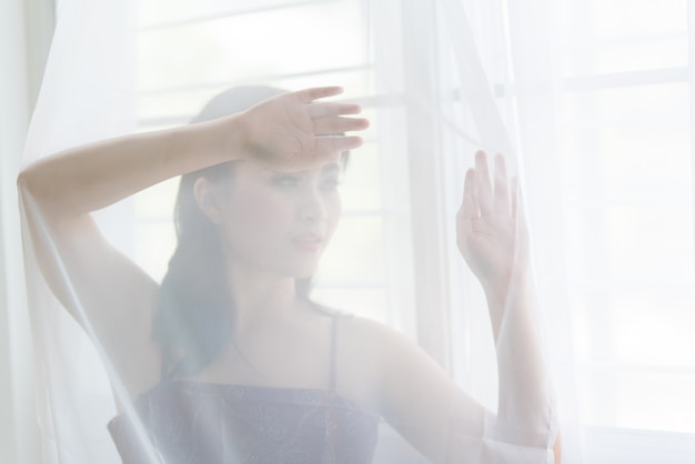 Woman hiding behind the curtain.