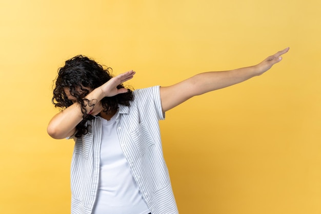 Woman hiding face with dab dance move performing internet meme of success dabbing trends