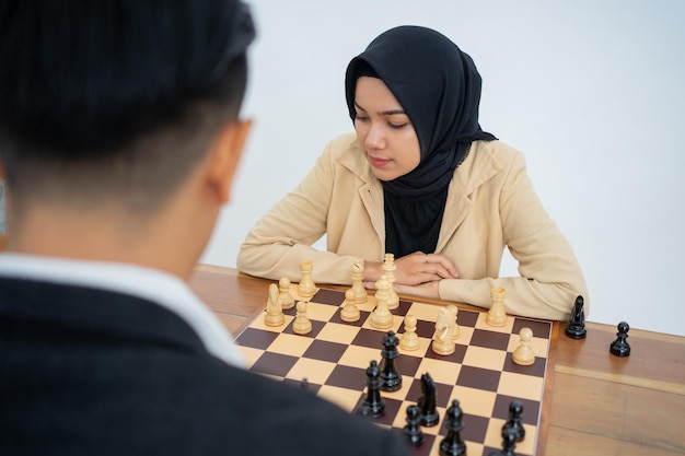 Woman in hijab against man while playing chess