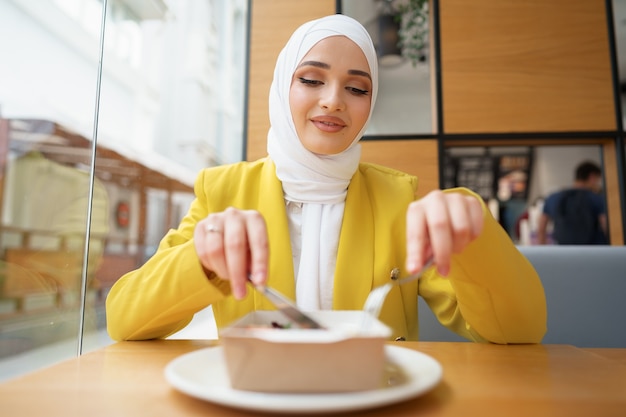 woman in hijab having lunch in cafe