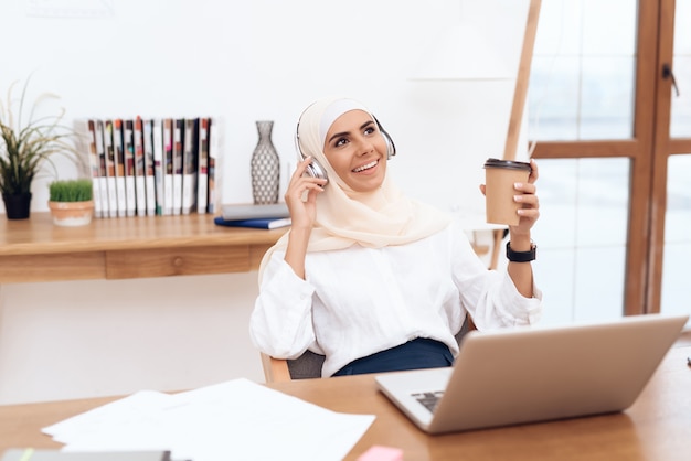 Woman in hijab listens to music on headphones