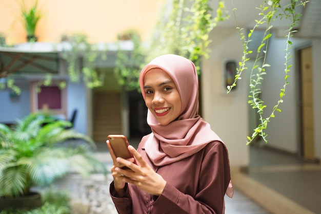 Foto una donna con l'hijab guarda il suo telefono.