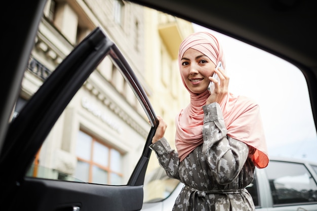 Donna in hijab aprendo la portiera della macchina