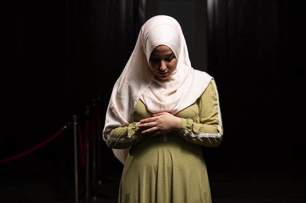 Женщина в хиджабе сидит в мечети и молится
