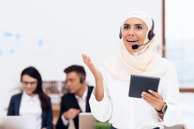 The woman in the hijab stands in the call center