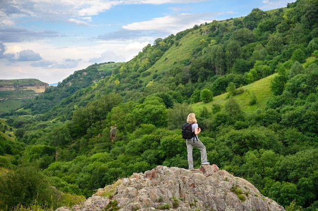 Woman hiker on mountain peak person tourist on forest background